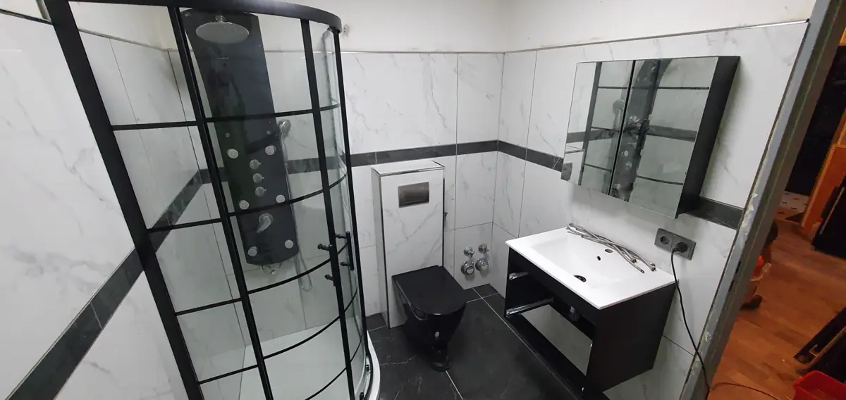 Das fertige Bad mit Eckdusche, schwarzem WC und Waschtisch mit Spiegelschrank