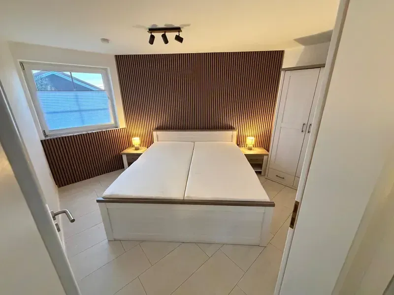 Dasselbe Schlafzimmer nach der Renovierung mit Akustik-Holzwand, Spotbeleuchtung und neuem Fliesenboden